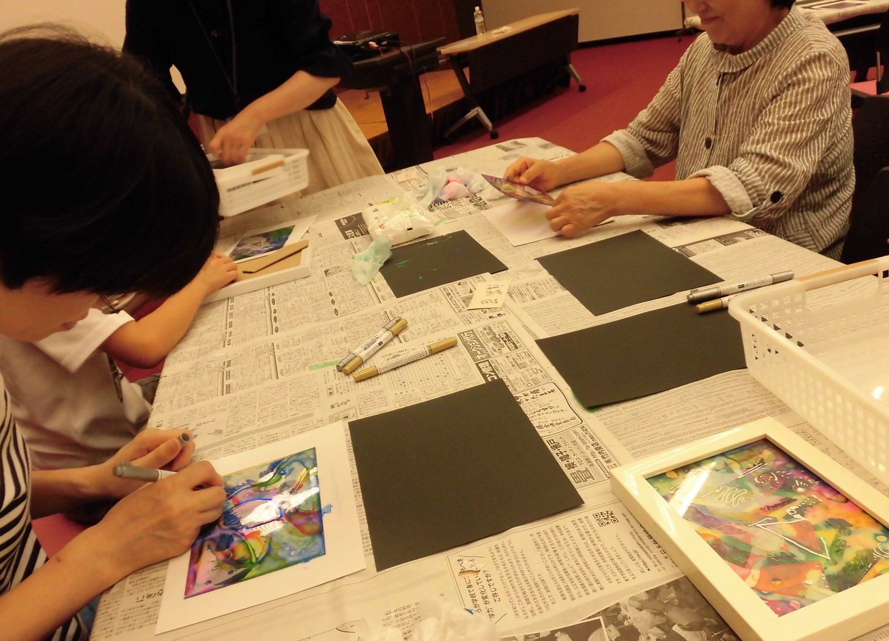 アクリル板に思い思いの色のインクを乗せ作品つくりに取り組む参加者の写真
