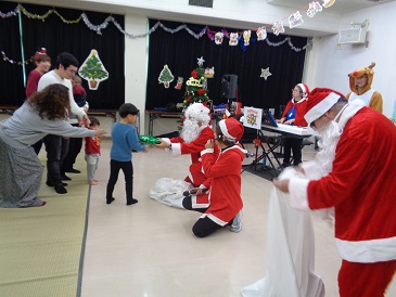 サンタさんにプレゼントをもらう子どもの写真