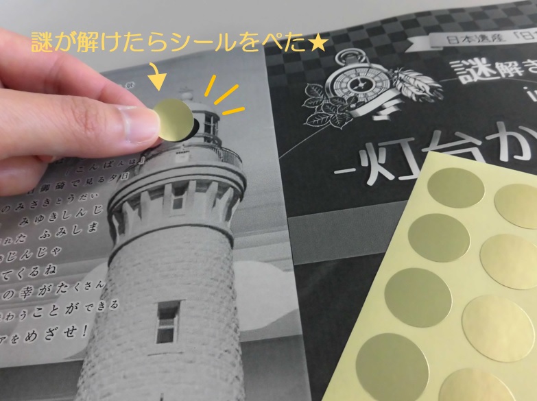 ガイドブックの灯台の写真に金色のシールを貼っている写真